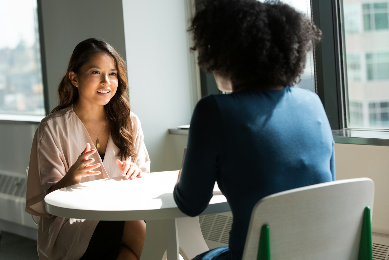 Coachmoment: coach en cliënt in gesprek aan een tafel